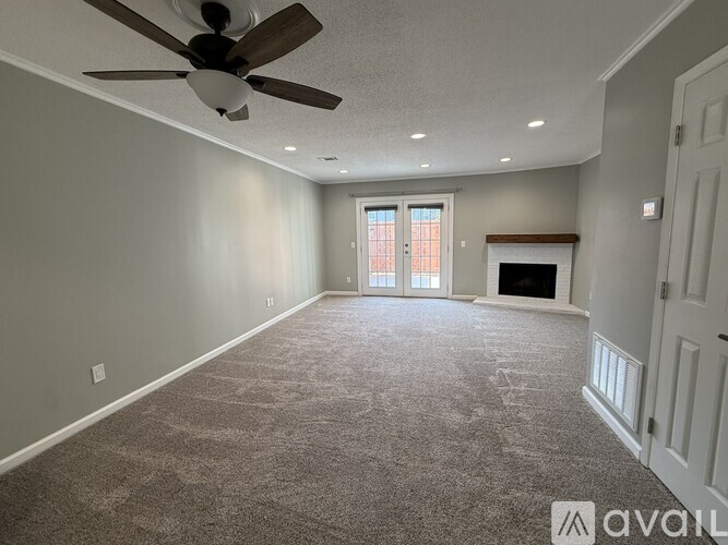 A spacious room with a ceiling fan and carpeted floor.