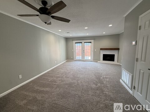 A spacious room with a ceiling fan and carpeted floor.