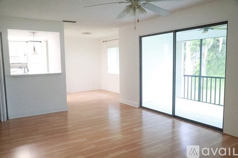 A spacious room with wooden floors and a ceiling fan.