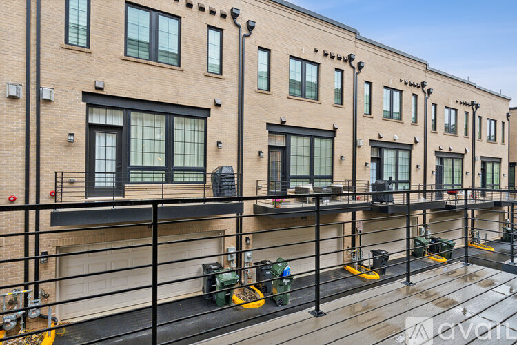 A row of brown buildings with green trash bins in front.