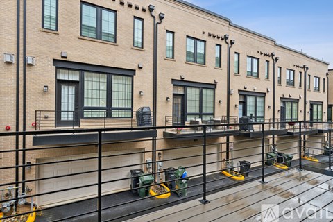 A row of brown buildings with green trash bins in front.