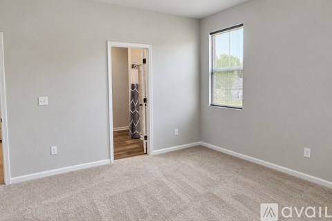 A spacious room with carpeted floor, two windows, and a door leading to another room.