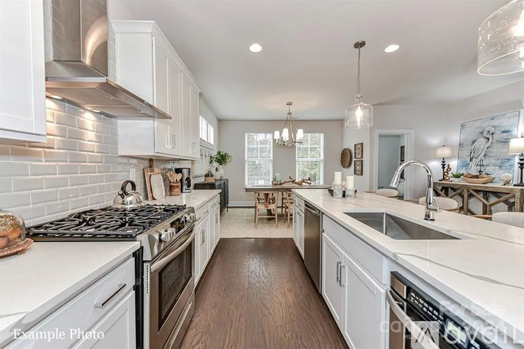 A modern kitchen with white cabinets and stainless steel appliances.