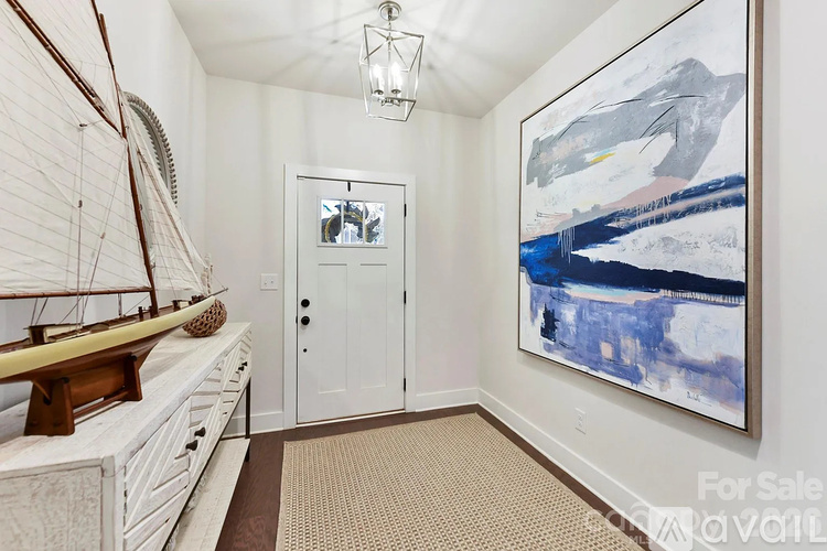 A room with a painting on the wall and a sailboat on the shelf.