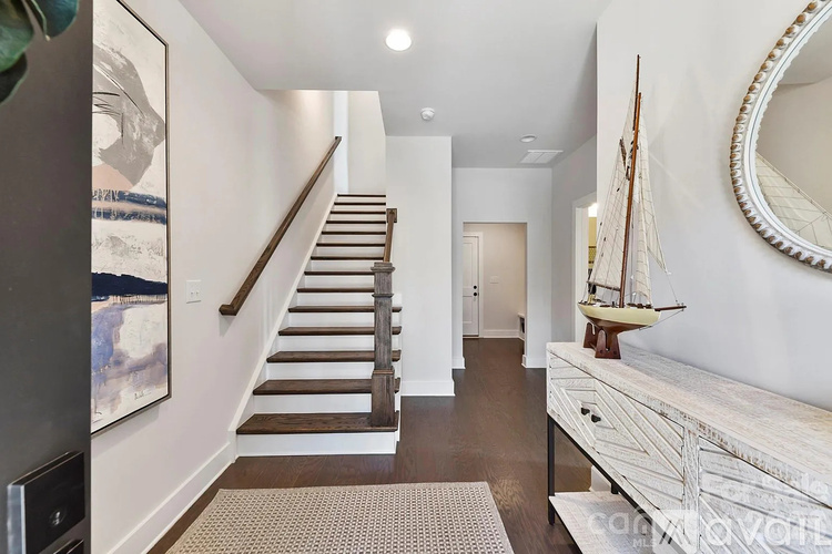 A hallway with a staircase, a mirror, and a sailboat decoration.