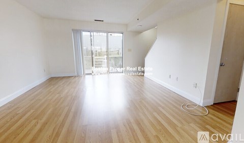 A spacious room with wooden flooring and a large window.