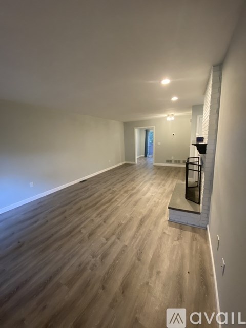A spacious room with wooden flooring and a white wall.