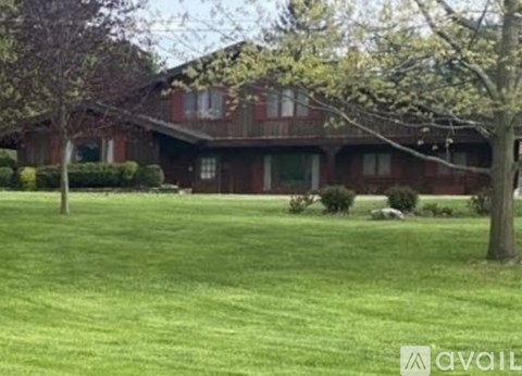 A house with a red brick exterior and a green lawn in front.