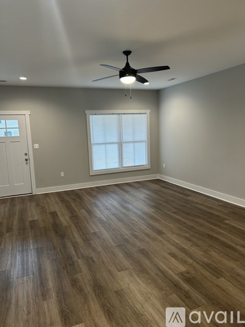 A room with a ceiling fan and wooden flooring.