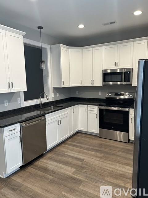 A kitchen with white cabinets and black countertops.