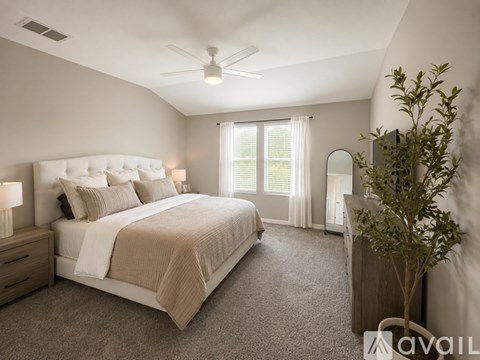 A bedroom with a large bed, a ceiling fan, and a window with blinds.