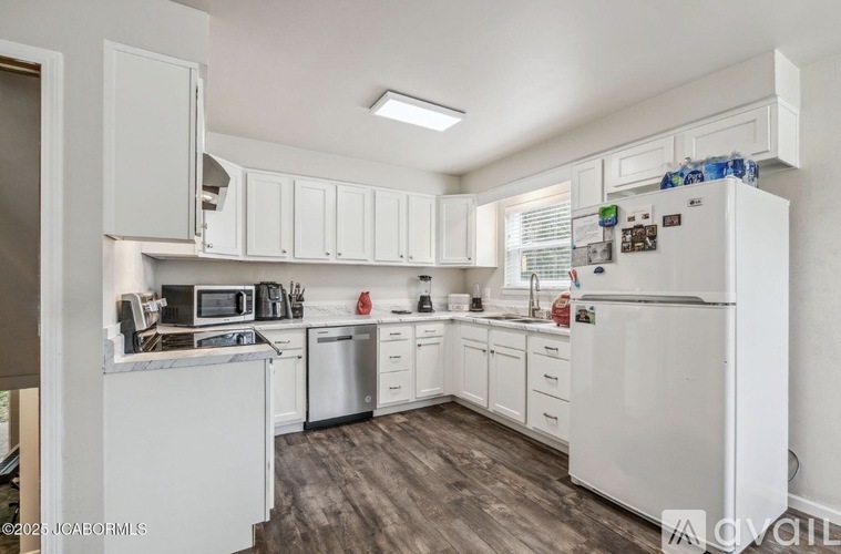 A kitchen with white cabinets and a white fridge.