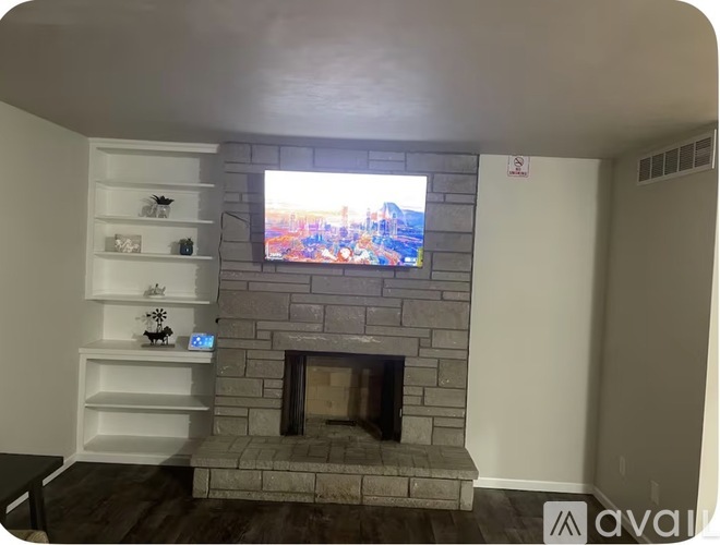 A modern living room with a stone fireplace and a television mounted above it.