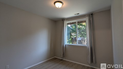 A room with a window and a view of trees outside.