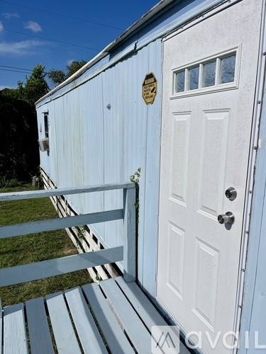 A white door with a window and a mailbox on a blue building.