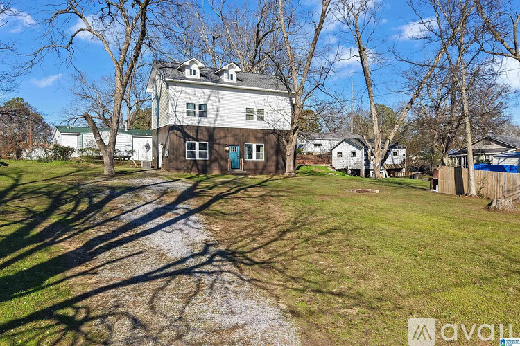 A house with a driveway and trees in front of it.