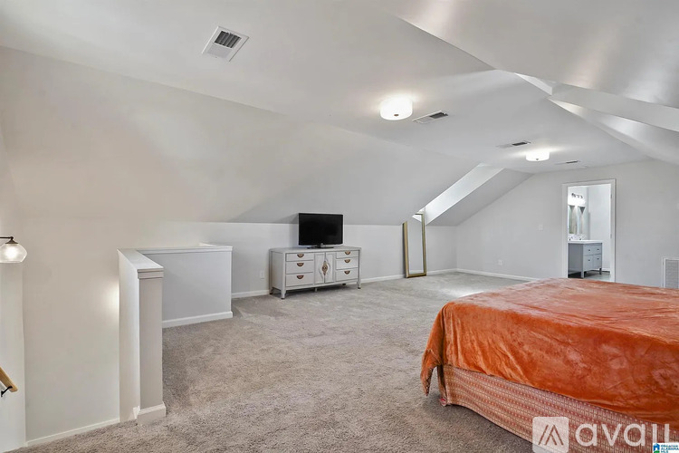 A bedroom with a bed covered in orange bedding and a white dresser.
