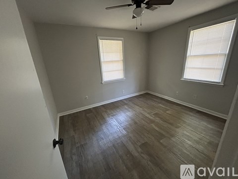 A room with a ceiling fan and two windows.