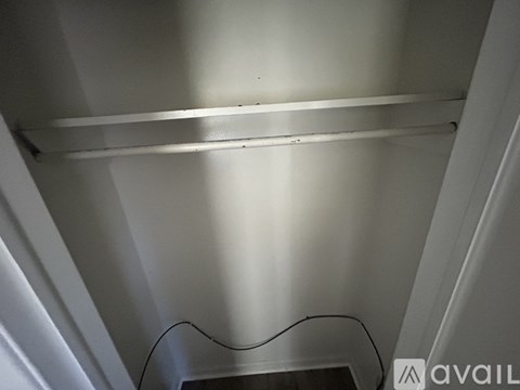 A white shelf in a room with a cable running along the bottom.
