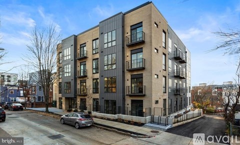 A modern apartment building with a car parked in front.