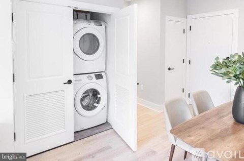 A washing machine is in a cabinet in a room with a table and chairs.