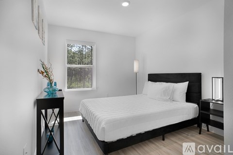 A bedroom with a large bed and a window overlooking a wooded area.