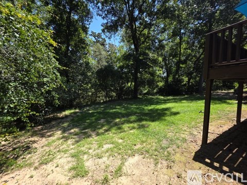 A wooden deck overlooks a grassy area with trees in the background.