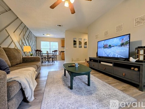 A living room with a couch, a coffee table, and a television.