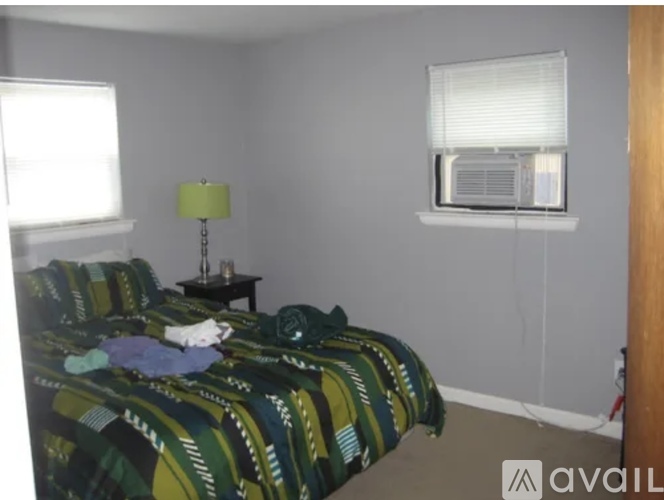 A bedroom with a bed covered in a green and black patterned comforter.
