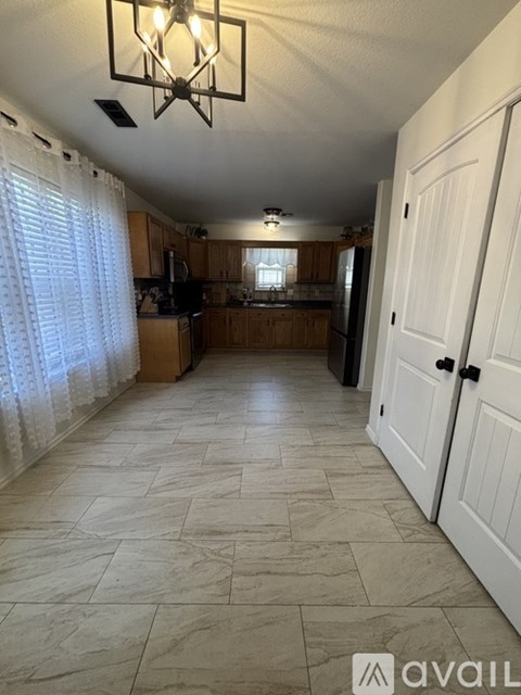 A kitchen with a large tiled floor and a chandelier hanging from the ceiling.
