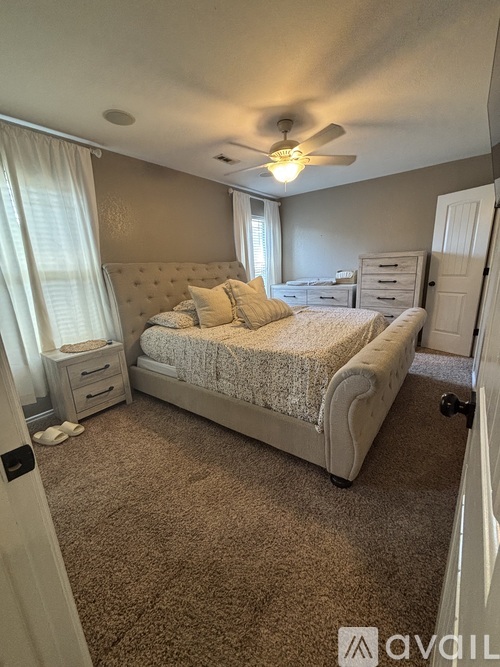A bedroom with a large bed and a ceiling fan.