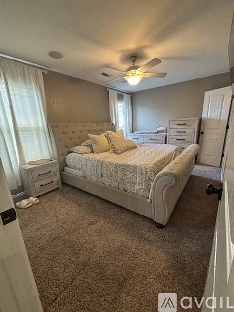 A bedroom with a large bed and a ceiling fan.