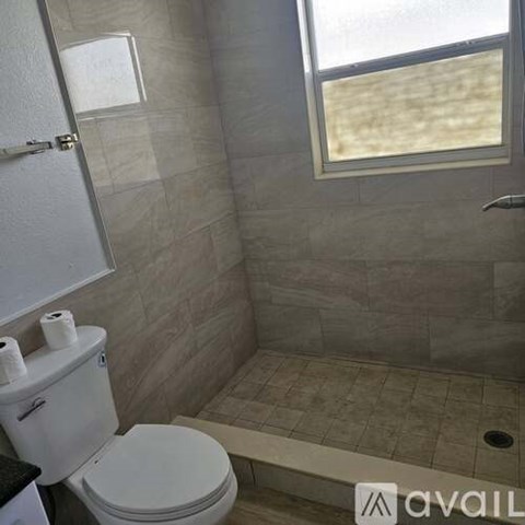 A bathroom with a toilet, a towel rack, and a window.