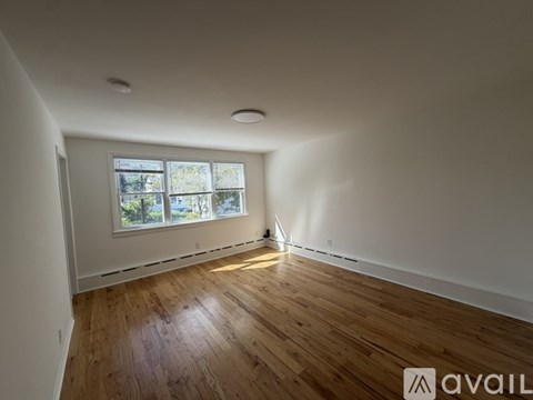 A room with wooden flooring and a window overlooking trees.