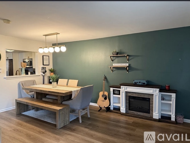 A living room with a wooden table and chairs, a fireplace, and a guitar.