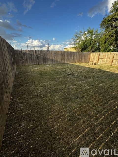 A backyard with a wooden fence and a grassy field.