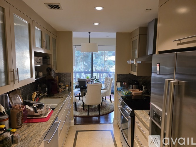 A kitchen with a refrigerator, sink, and a dining table.