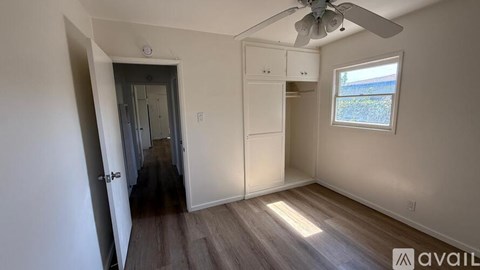 A room with a ceiling fan and a window with a view of a field.