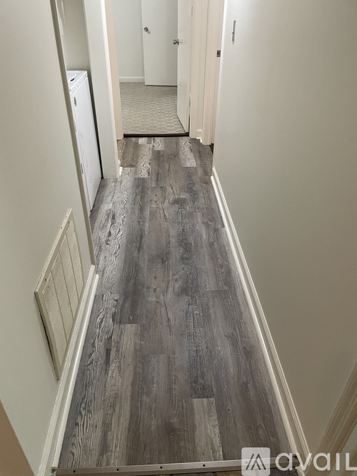 A hallway with wood flooring and white walls.