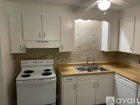 A kitchen with a white stove and cabinets.