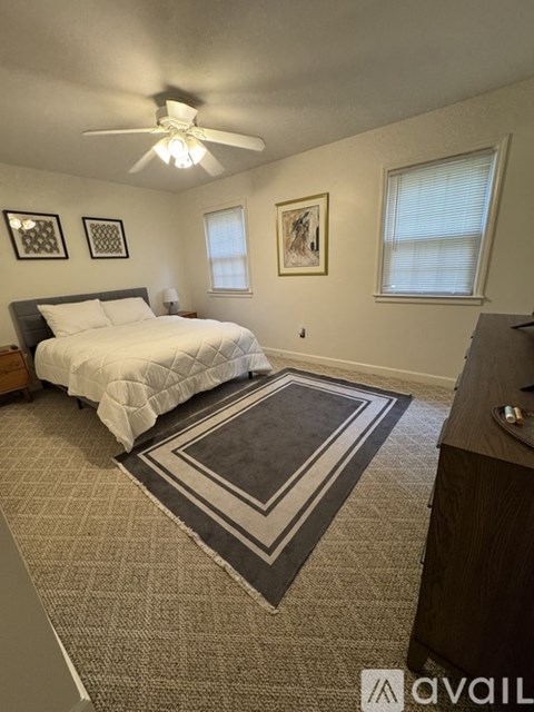 A bedroom with a bed, a rug, and two pictures on the wall.