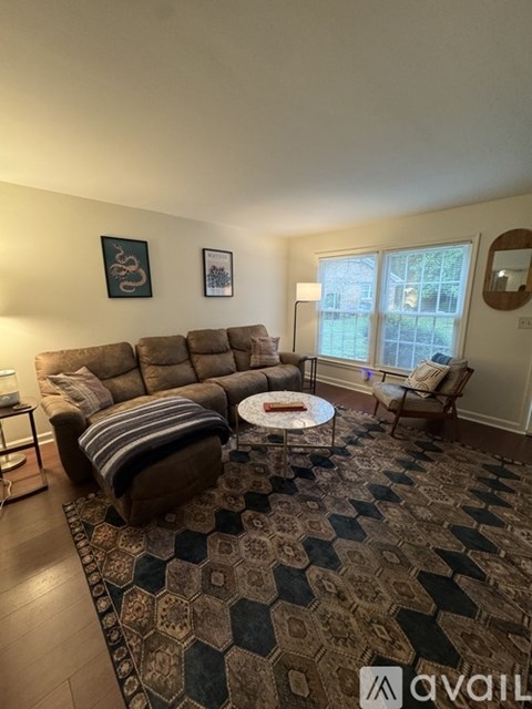 A living room with a brown couch, a round coffee table, and a rug with a geometric pattern.