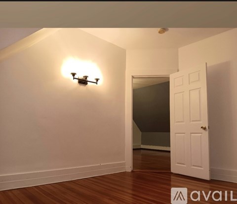 A drone is flying in a room with white walls and wooden floors.
