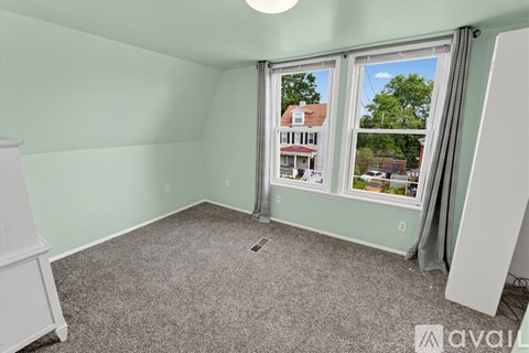 A room with a carpeted floor, a window with a view of a house outside, and a white dresser.