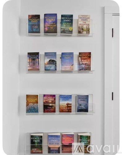 A white refrigerator with a magnet holding a series of books by Nicholas Sparks.