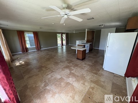 A spacious room with a ceiling fan and tiled flooring.