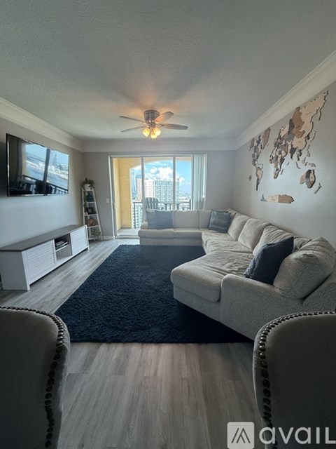 A living room with a grey couch and a world map on the wall.