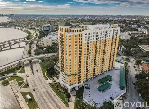 A tall yellow building with a green roof is surrounded by roads and other buildings.