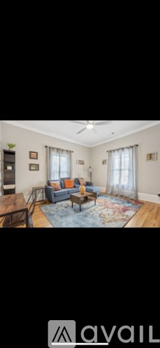A living room with a blue couch and a rug.