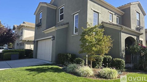 A house with a garage and a tree in front.